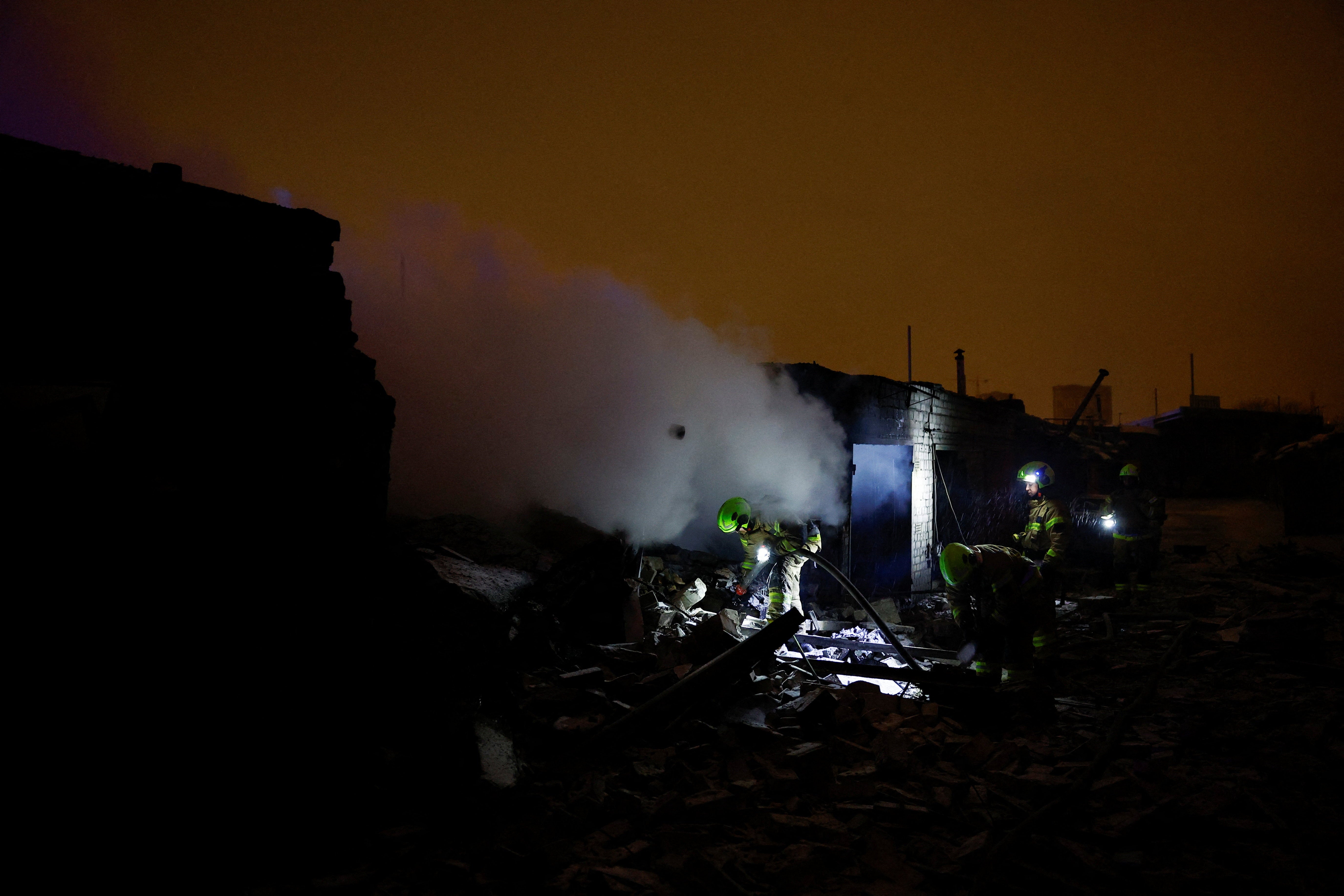 Firefighters work at a compound of car garages damaged during a Russian drone and missile attack in Kyiv