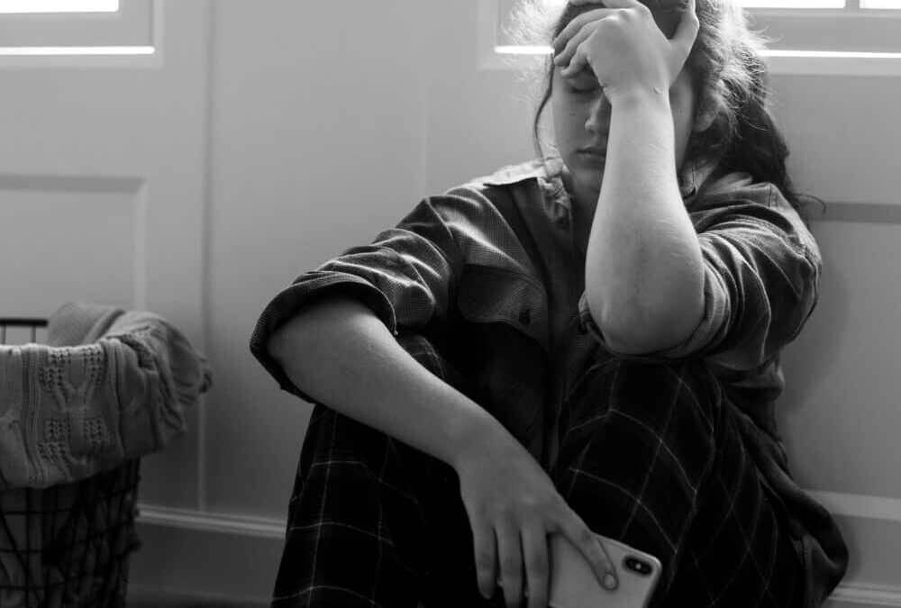 Teen sitting alone with phone, illustrating the dangers of AI mental health support and artificial intelligence influencing vulnerable youth.