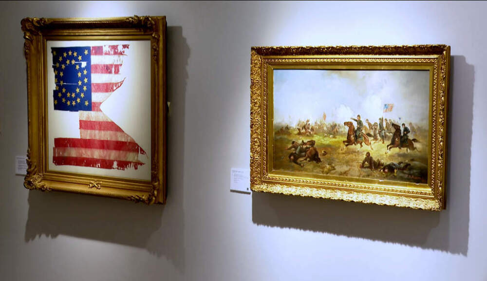 A flag known to have survived from the battlefield on the Little Bighorn River carried by George Custer's battalion, left, and a painting titled, "General Custer Leading the Wolverines at Gettysburg" by Franklin Dullin Briscoe, hang on display at Christie's. (Joe Frederick/AP)
