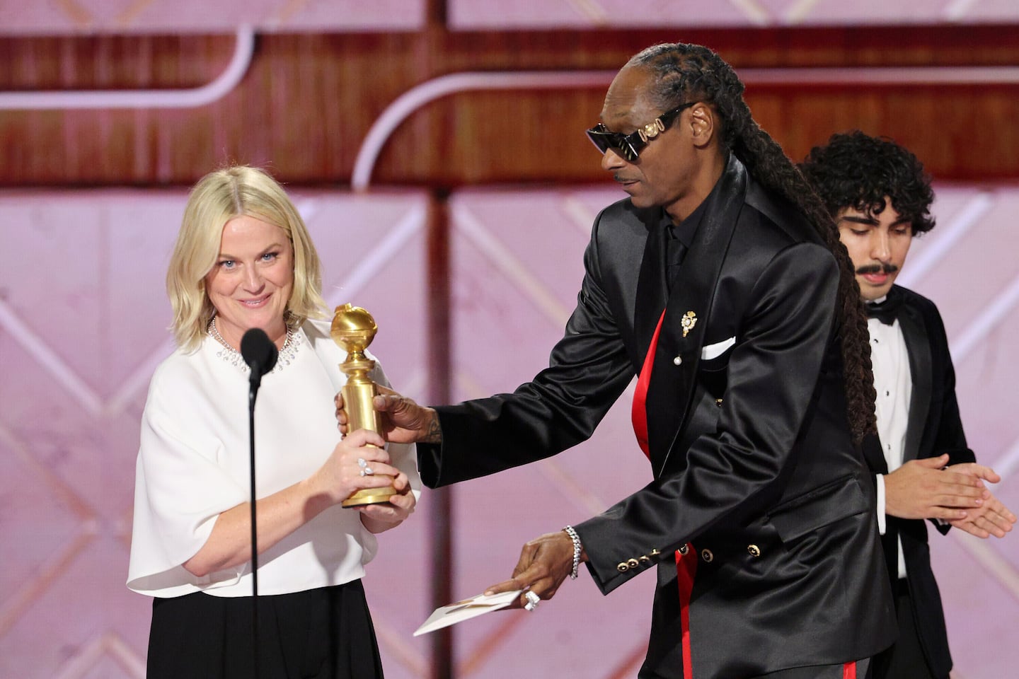 This image released by CBS Broadcasting shows Amy Poehler, left, accepting the award for best podcast for "Good Hang with Amy Poehler" from presenter Snoop Dogg during the 83rd Golden Globes on Sunday at the Beverly Hilton in Beverly Hills, Calif. 