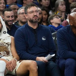Golden State Warriors assistant coach and New York Liberty head coach Chris Demarco, middle, sits between Warriors guard Stephen Curry, left, and Warriors assistant coach Jerry Stackhouse during an NBA basketball game against the Utah Jazz in San Francisco, Monday, Nov. 24, 2025. (AP Photo/Jeff Chiu)
