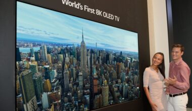 A man and woman standing next to a TV labeled the "world's first 8K OLED TV."