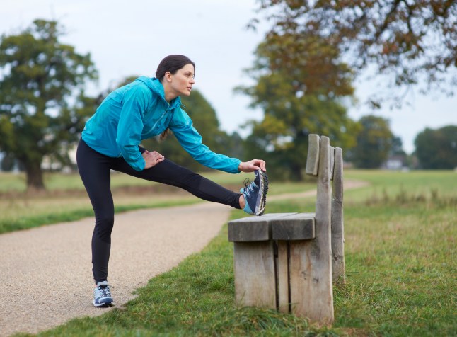 Female runner stretching on park bench.