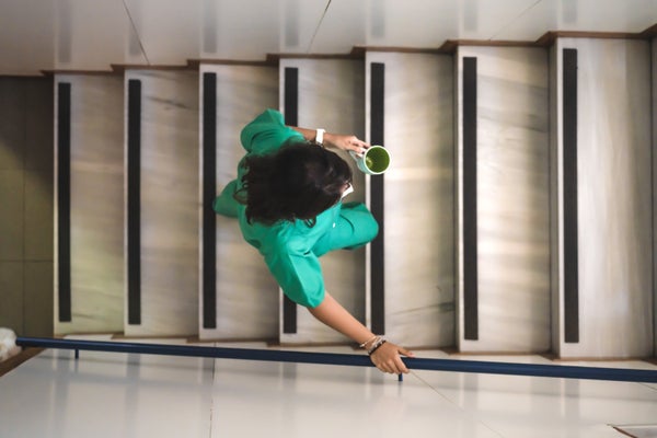 a woman in a nurse uniform holding a cup of coffee walks up stairs