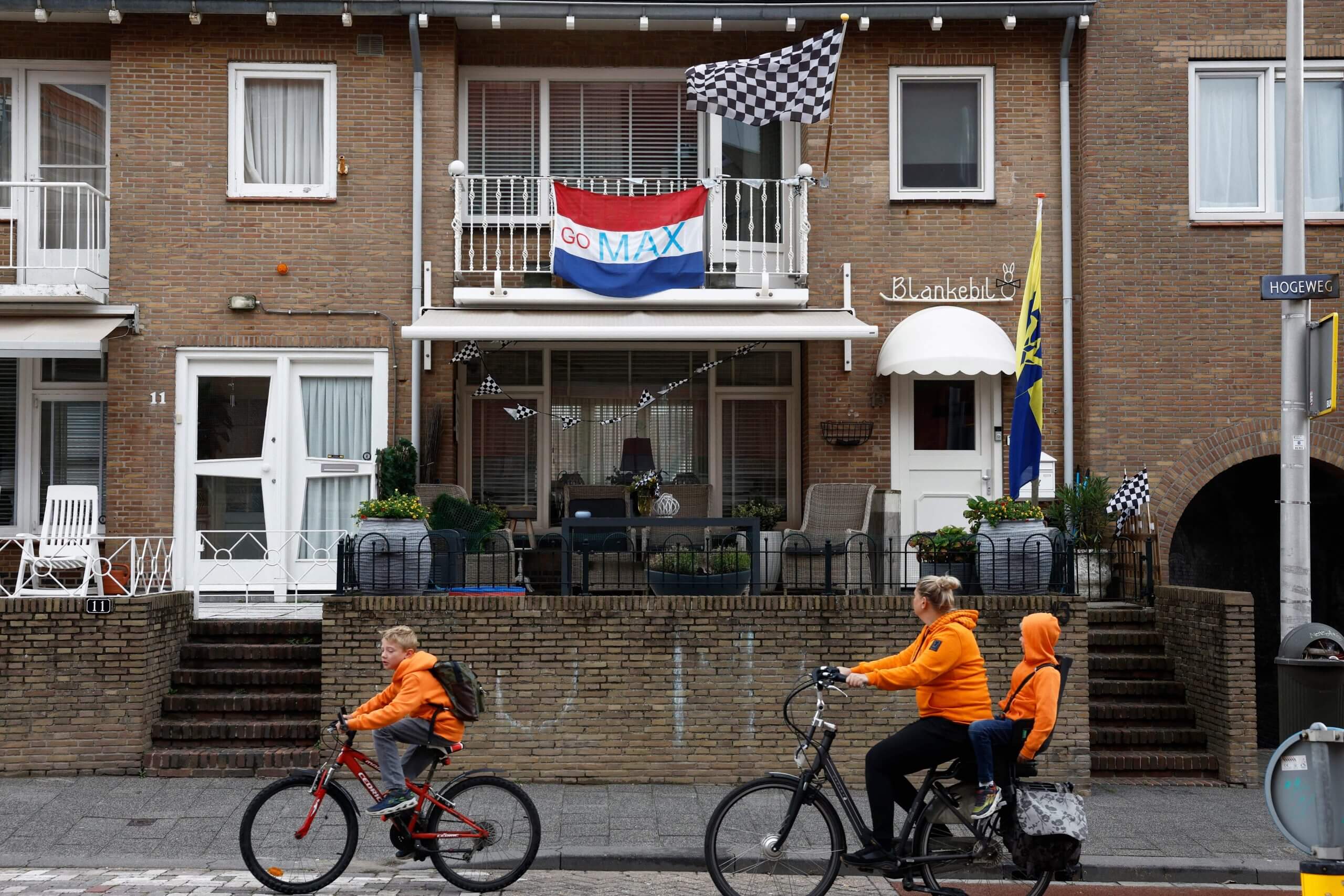 Cyclists wearing orange cycle past a house in the Netherlands