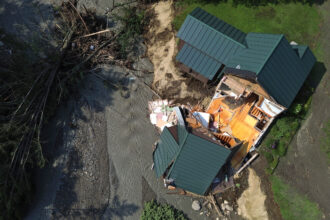 An aerial view of a partially collapsed home in St. Johnsbury, Vt., on July 30, 2024, after flash floods hit the area. Vermont, along with New York, passed climate superfund laws last year, and similar legislation is pending in a handful of other states. Credit: Danielle Parhizkaran/The Boston Globe via Getty Images