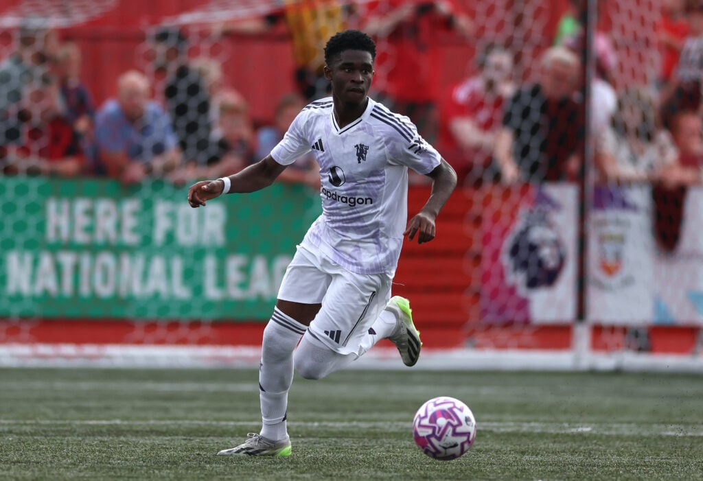 Jaydan Kamason dribbling in white Manchester United kit.