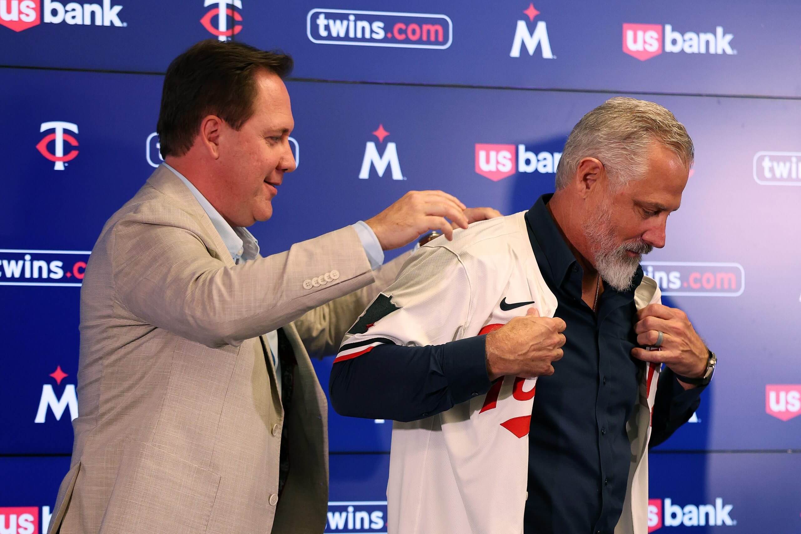 Derek Falvey helps Derek Shelton put on a Minnesota Twins jersey during Shelton's introductory news conference.