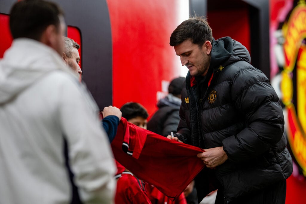 Harry Maguire signs his autograph for a young fan ahead of the Premier League match between Manchester United and Bournemouth at Old Trafford in 2025 in Manchester, England.