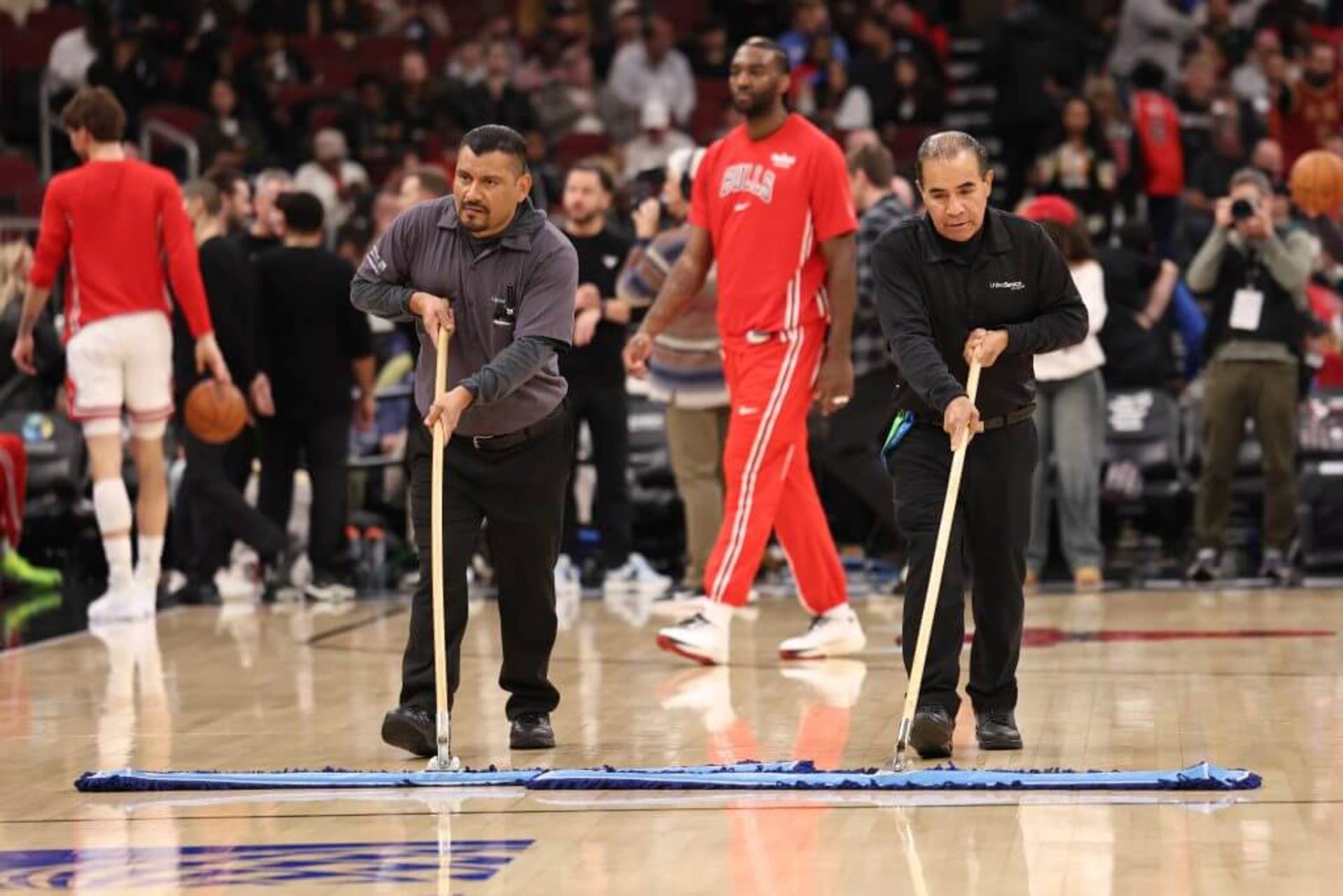 Maintenance staff wipes the floors during a delay in a game between the Chicago Bulls and the Miami Heat at the United Center on January 8, 2026 in Chicago, Illinois.
