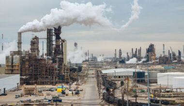 An aerial shot shows billowing white emissions from stacks in the large complex.