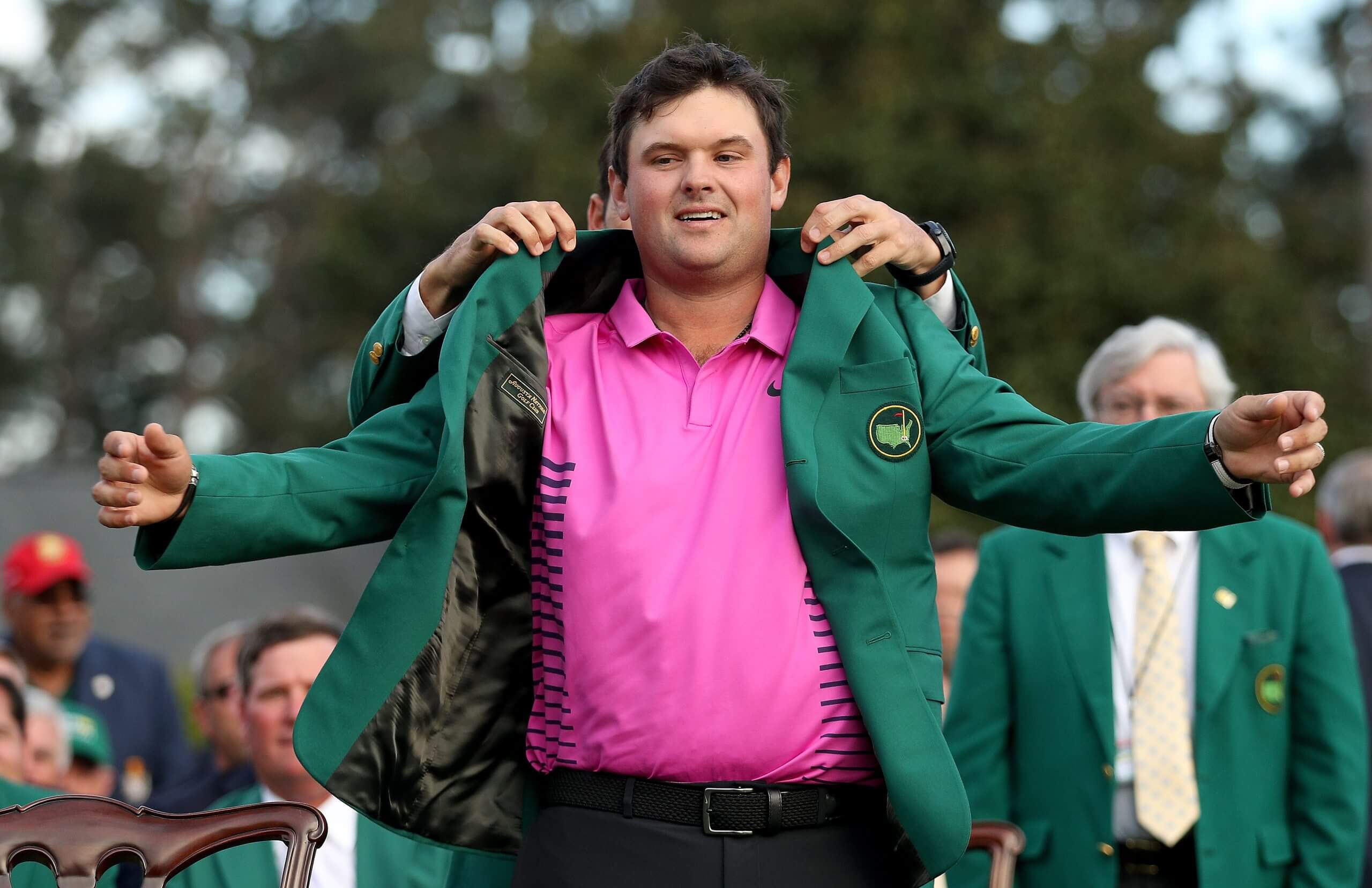 Patrick Reed has his green jacket slipped onto his shoulders by Sergio Garcia in 2018.