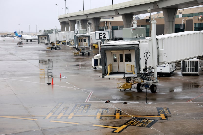 The gates and jet ways stand empty around DFW Airport’s Terminal E after numerous flights...
