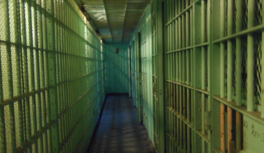 Hallway of prison cells; image by HoBoTrails12AM, via Pixabay.com.