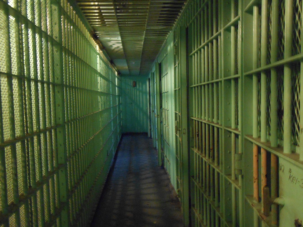 Hallway of prison cells; image by HoBoTrails12AM, via Pixabay.com.