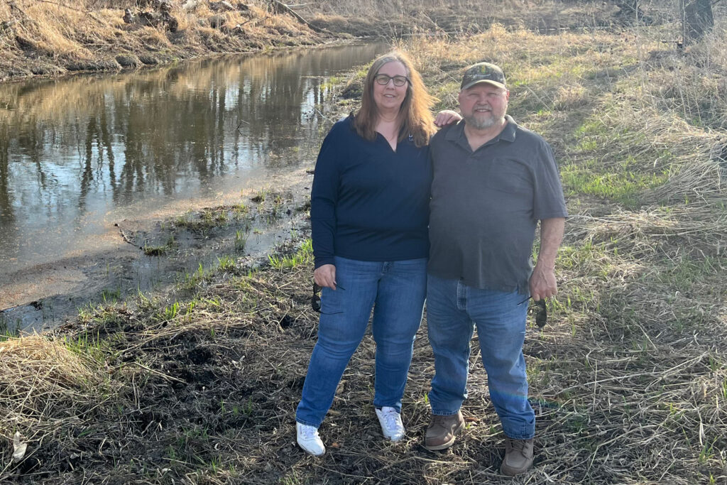 Kathy and David Law stand next to a restored oxbow on their farm in Carroll County, Iowa. Credit: Courtesy of Kathy Law