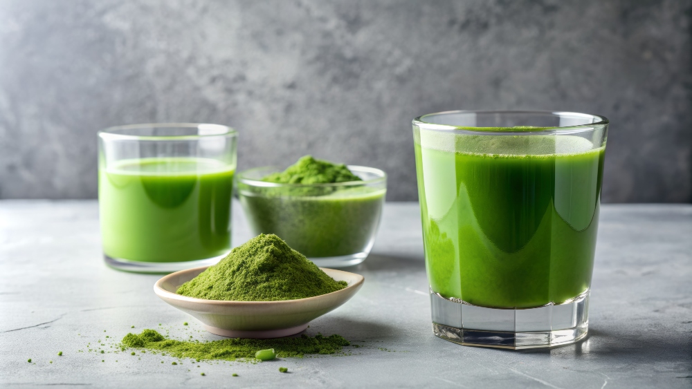 Chlorella drink in a glass and its powdered form in a bowl on a white concrete background, to showcase the dangers of spirulina