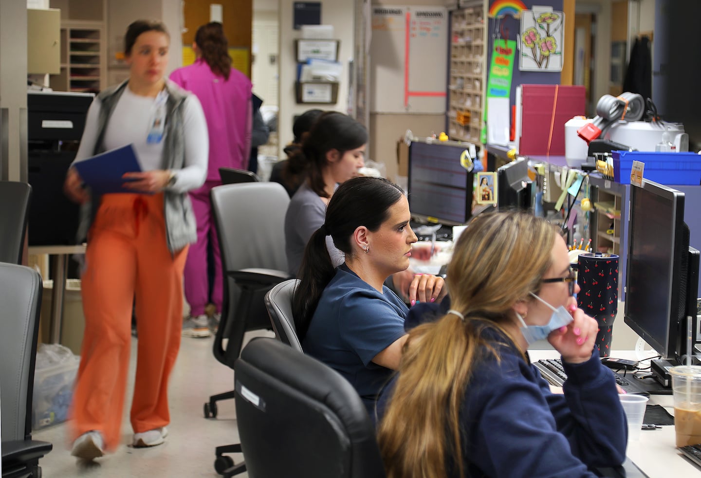 Nurse Meghan Gillis (center) sits at a computer terminal studying patients' records as other nurses fill the nurses station in the Ellison Unit at Mass General Hospital, where rooms are filled with patients on Jan. 23.