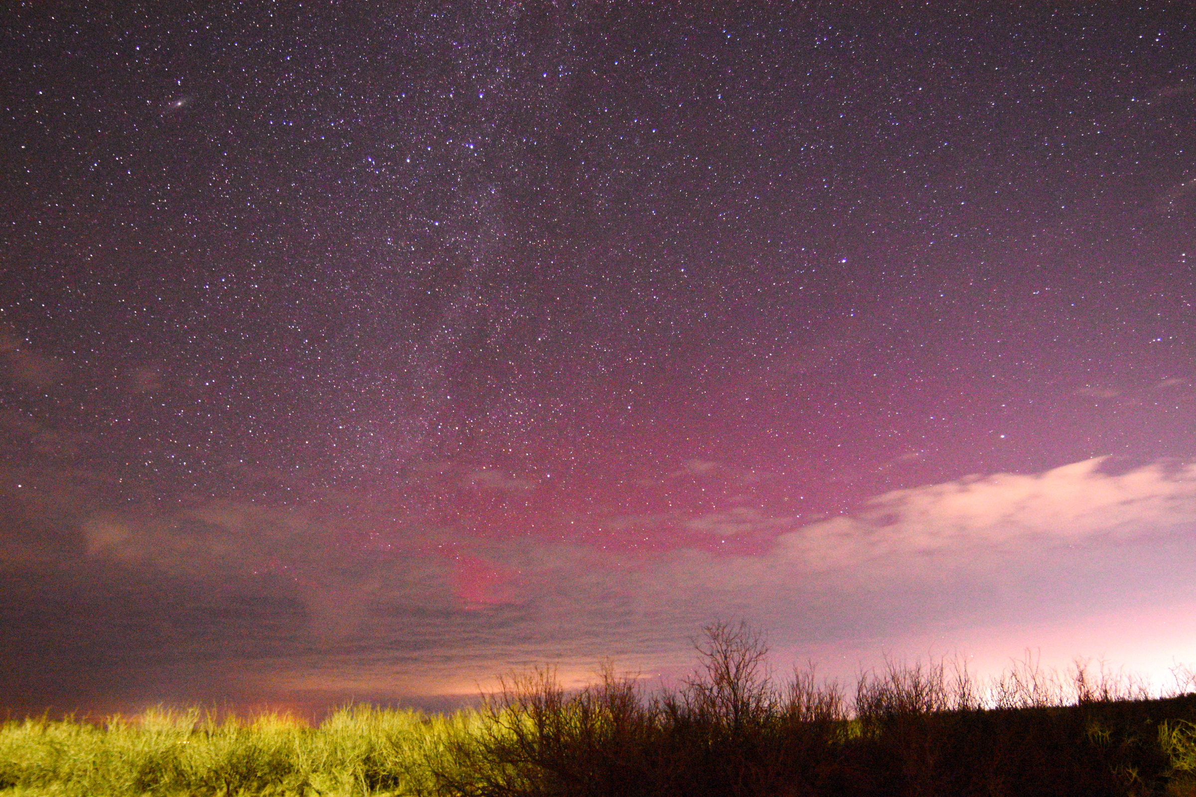 red northern lights against a starry sky with some clouds.