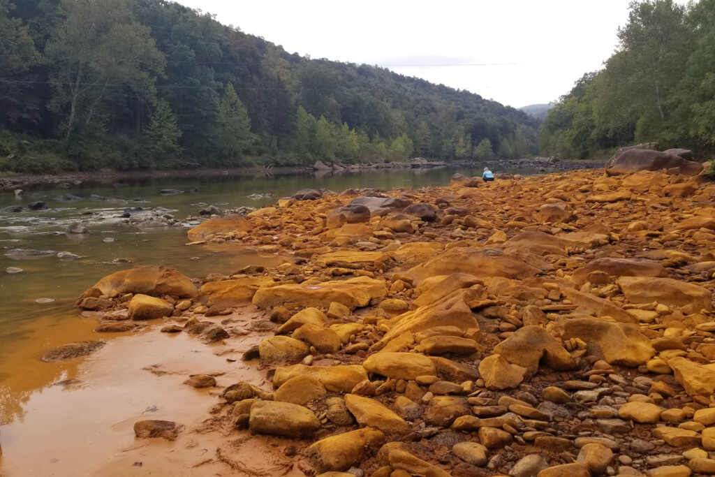 Lick Run, a tributary to West Virginia’s Cheat River, is one of many waterways in Appalachia that are impaired by pollution from coal mining. Acid mine drainage can create a reddish coloring in affected streams. Credit: Courtesy of Friends of the Cheat