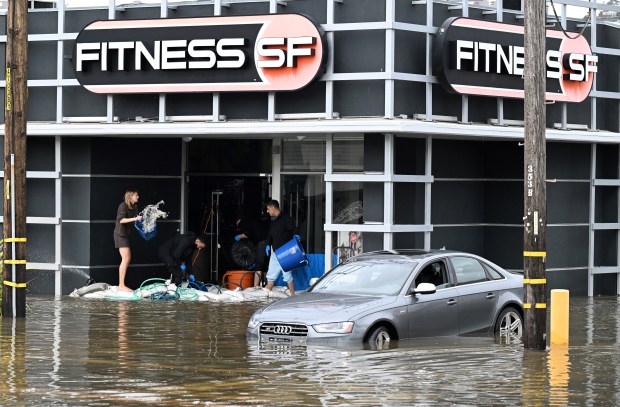 People bail water at the flooded entrance of Fitness SF on Fifer Avenue in Corte Madera, Calif., on Friday, Jan. 2, 2026. The flooding happened during a period of rain and king tides. (Sherry LaVars/Marin Independent Journal)
