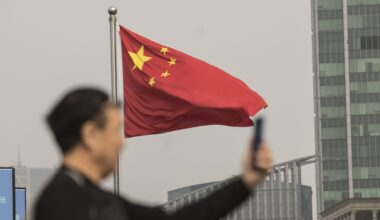 Man looking at phone on backdrop of Chinese flag