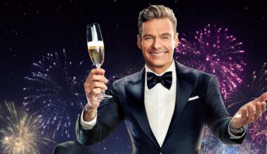 A beaming Ryan Seacrest raises a glass of champagne to welcome in the New Year, dressed in a tuxedo and bow tie and with colorful fireworks exploding in the background.