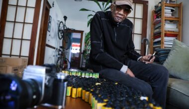 Charles Daniels posed for a portrait near a small portion of his thousands of undeveloped rolls of film in 2022.