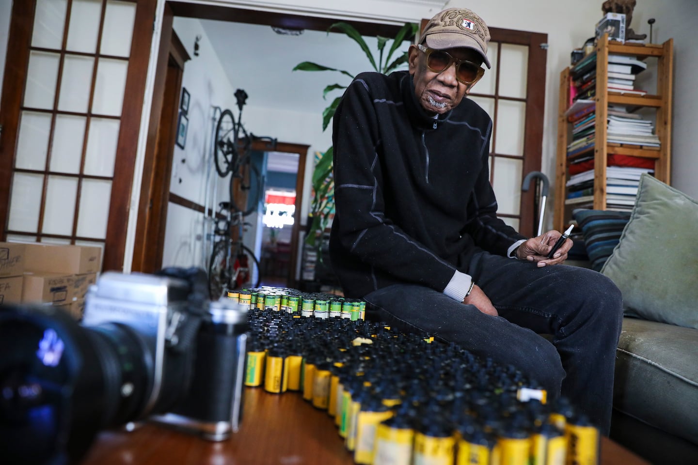 Charles Daniels posed for a portrait near a small portion of his thousands of undeveloped rolls of film in 2022.