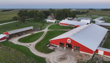 An aerial view of a farm with a red barn and several buildings around it.