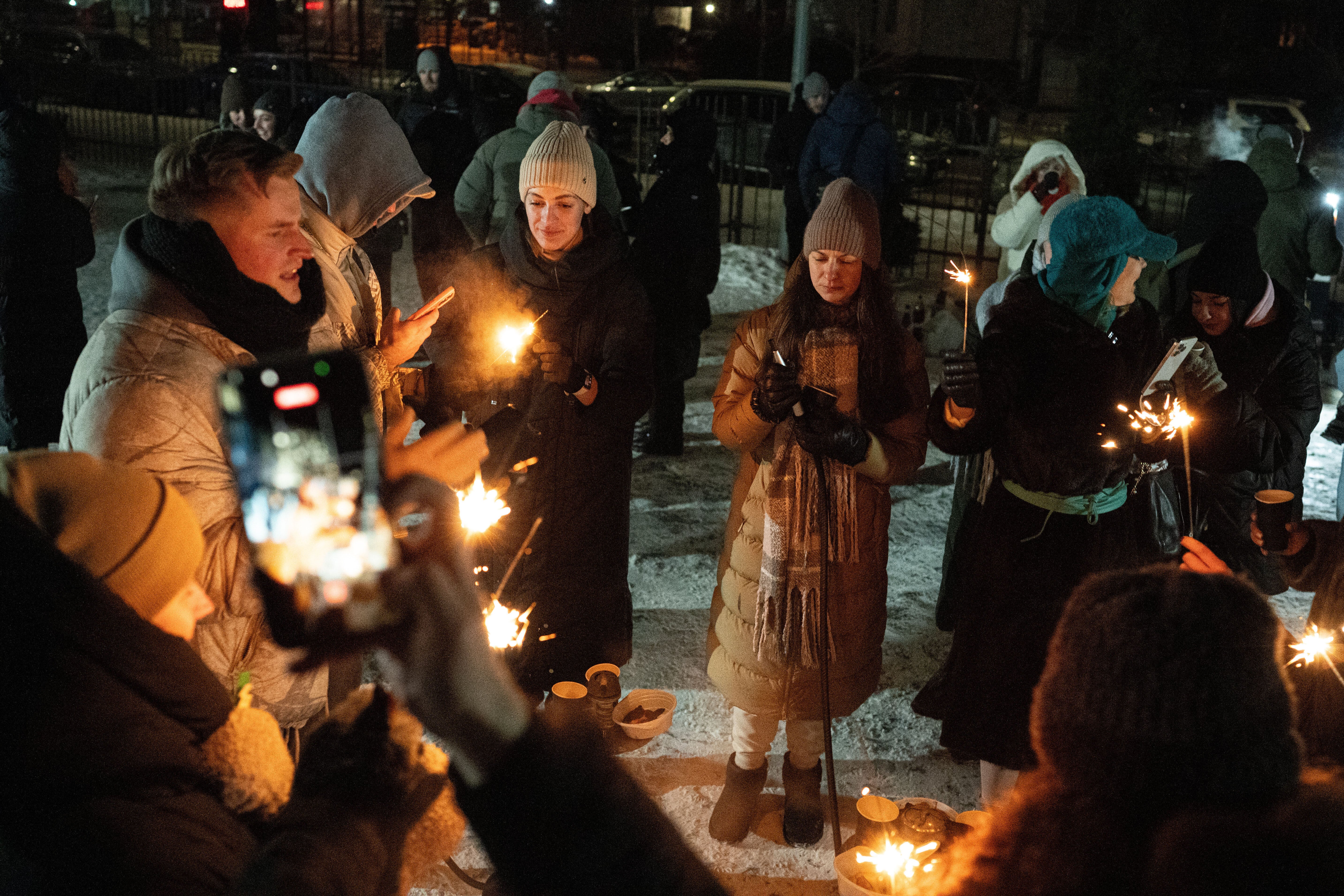 People warm up outside their multistory buildings during a power outage caused by Russia's regular air attacks on the country's energy sector that leave residents without power, heating and water in Kyiv