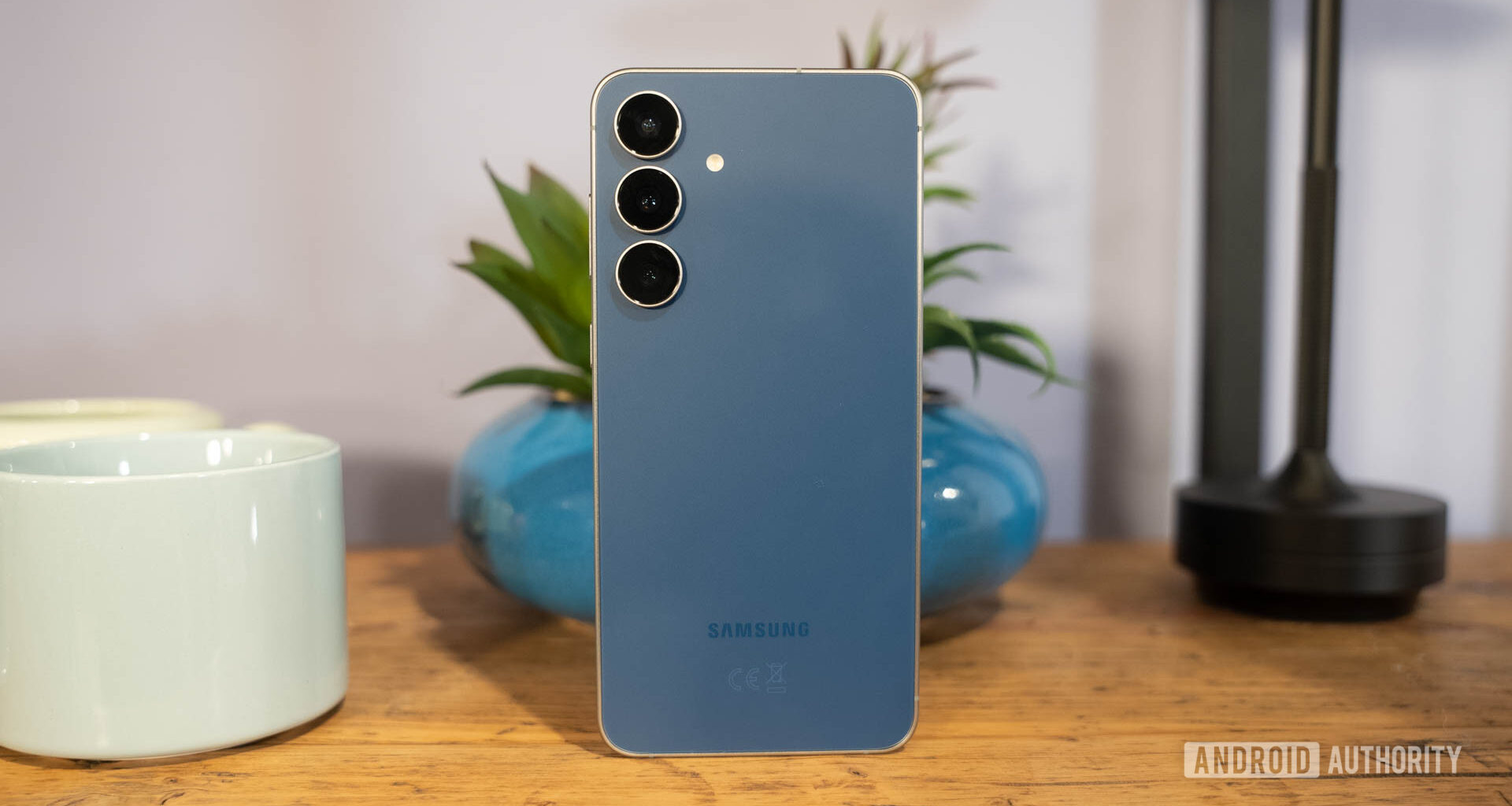 Samsung Galaxy S25 FE in Navy standing in front of plant