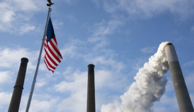 Emissions rise from a smokestack alongside an American flag in Ohio.