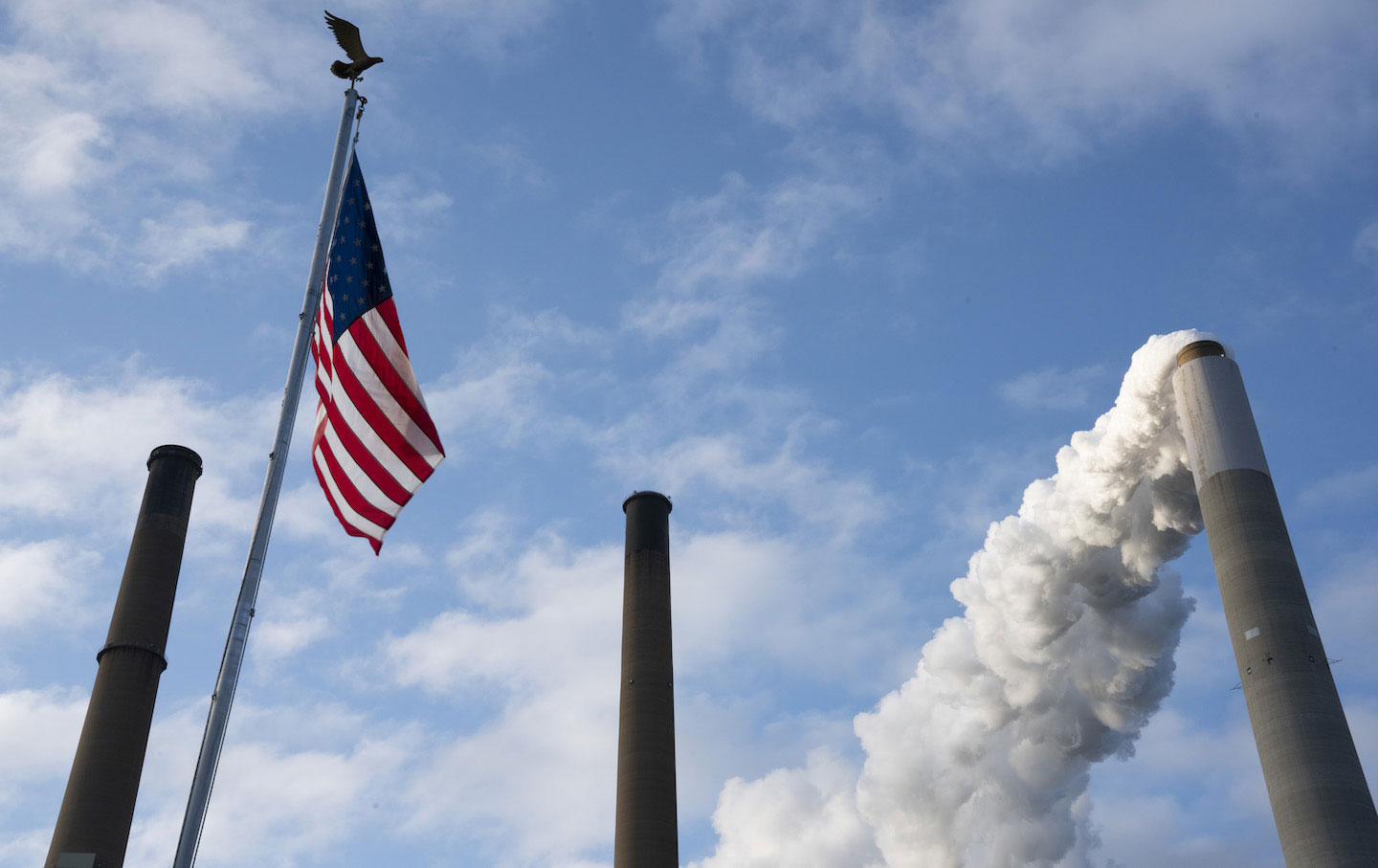 Emissions rise from a smokestack alongside an American flag in Ohio.