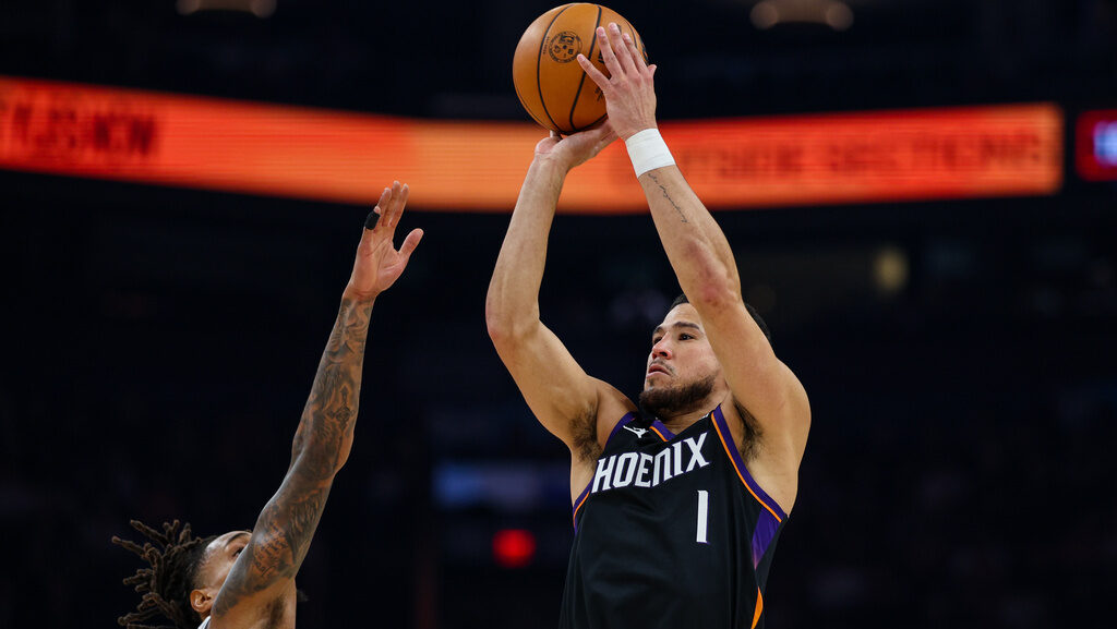 Phoenix Suns guard Devin Booker (1) goes up to shoot over San Antonio Spurs guard Devin Vassell, le...
