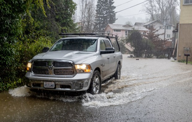 Mill Court resident Steven Kline heads out for higher ground as the stormwater begins to flood his Guerneville neighborhood Monday Jan 5, 2026. Kline credits the county for clearing the nearby creek and reducing the height of the flood waters. (John Burgess / The Press Democrat)