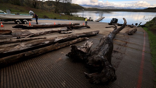 Juilan Navarro, left, and Rudy Aguilar with Army Corps of Engineers finish up pulling dead oak and pine trees ashore after copious flash flooding dislodged timber from tributaries which drain in to Lake Sonoma, Tuesday, Jan. 6, 2025. , (Kent Porter / The Press Democrat)