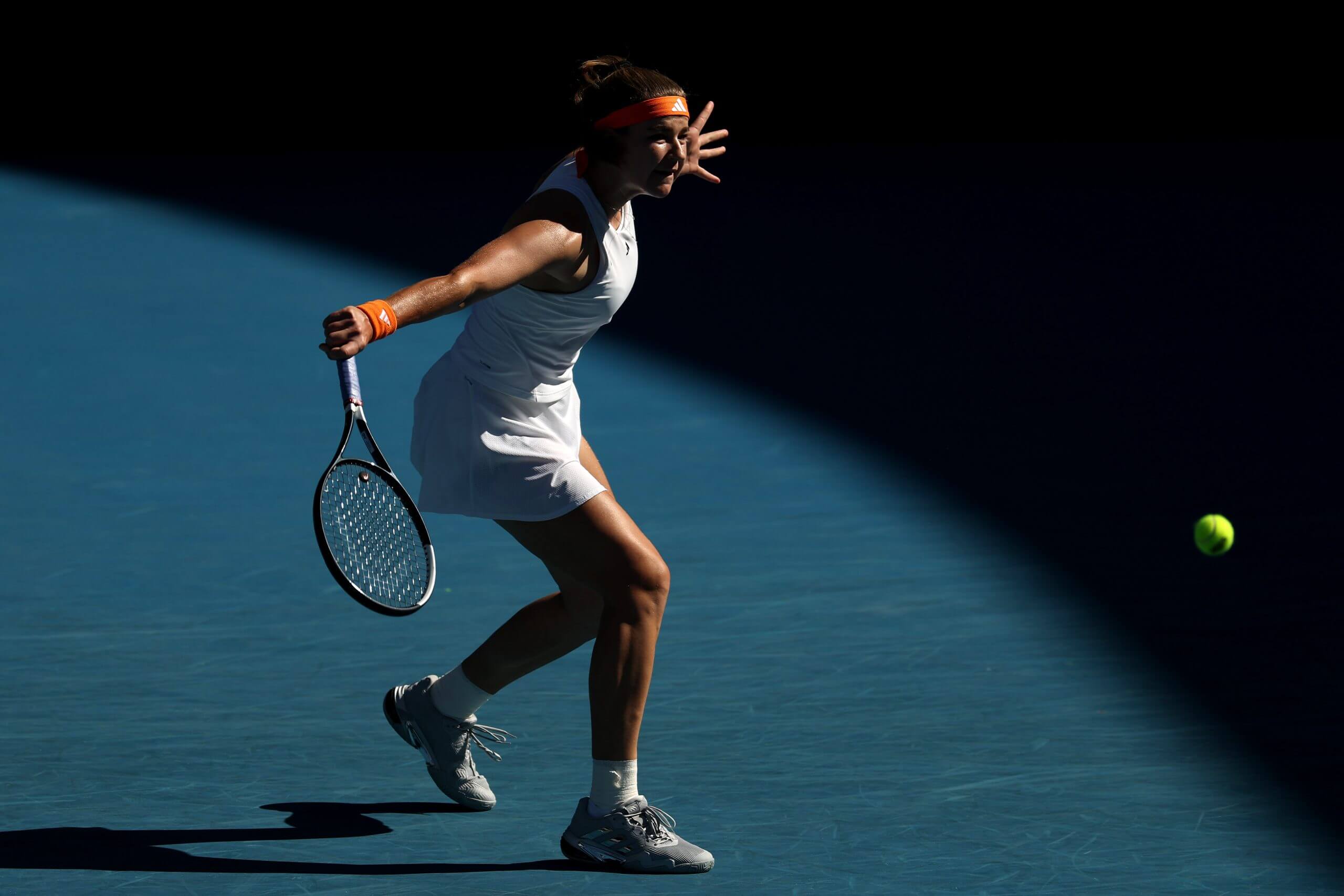 Karolína Muchová moves through a slice backhand with the ball out in front of her racket.