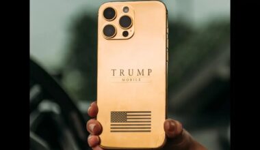 A gold smartphone with three camera lenses on the back features the text 'TRUMP MOBILE' and an engraved American flag design.