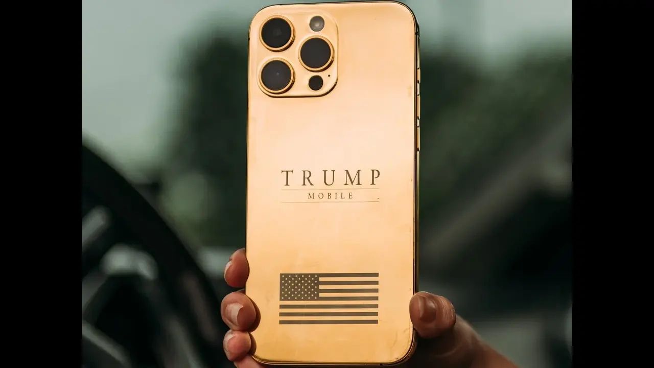 A gold smartphone with three camera lenses on the back features the text 'TRUMP MOBILE' and an engraved American flag design.