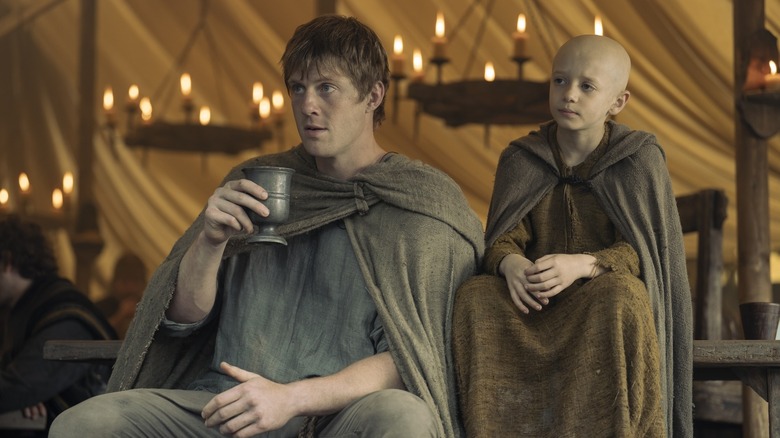 Dunk sitting and drinking from a metal cup while Egg sits beside him in A Knight of the Seven Kingdoms