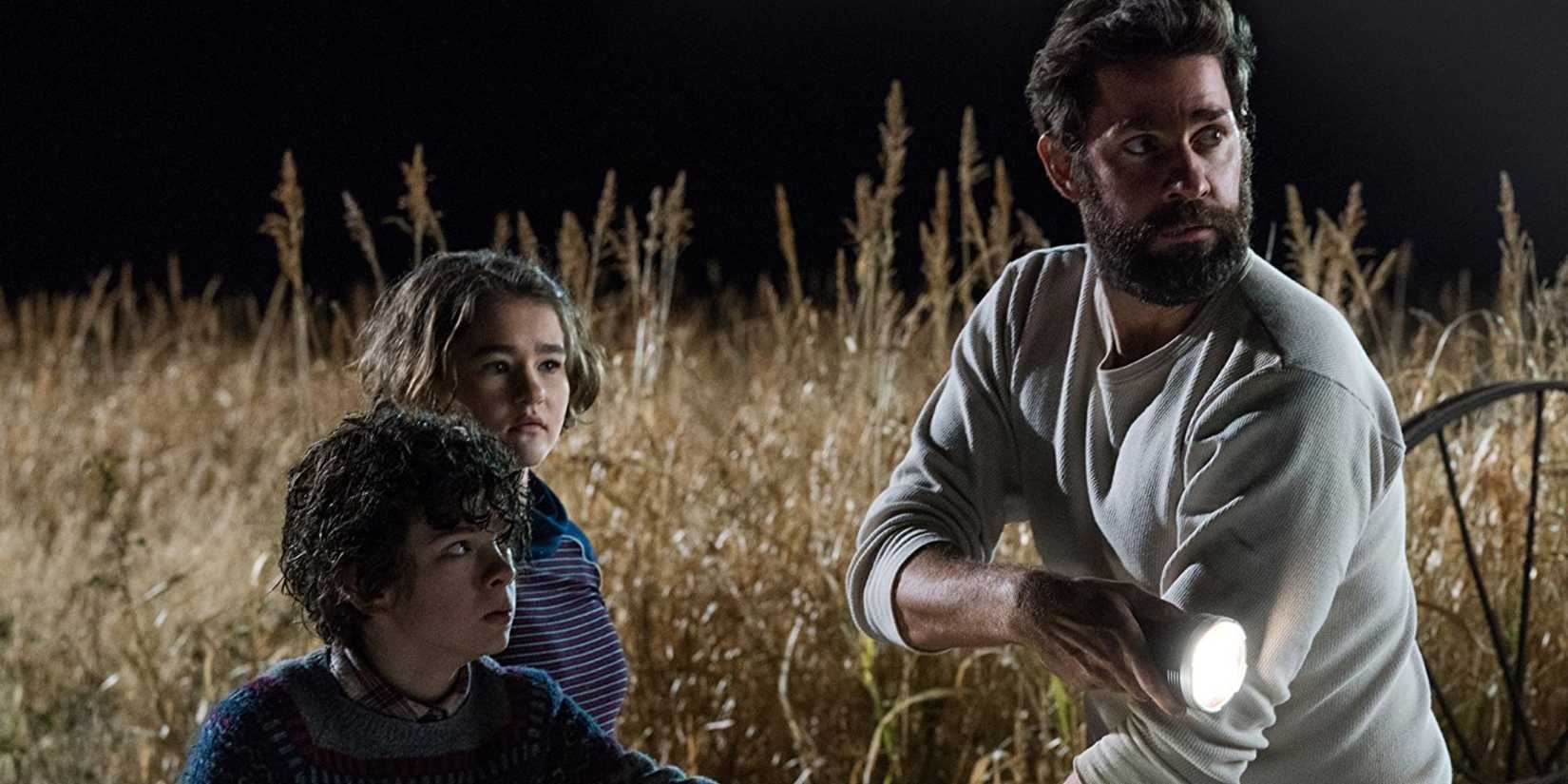 Lee Abbott (John Krasinski) leads Marcus (Noah Jupe) and Regan (Millicent Simmonds) through a wheat field at night in A Quiet Place