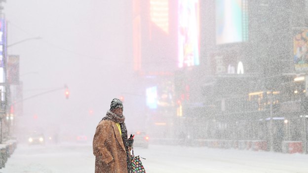 A pedestrian waits to cross the street near Times Square in New York.