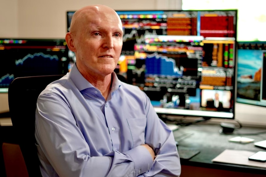 Sean Callow seated at desk with Bloomberg terminal screens behind him