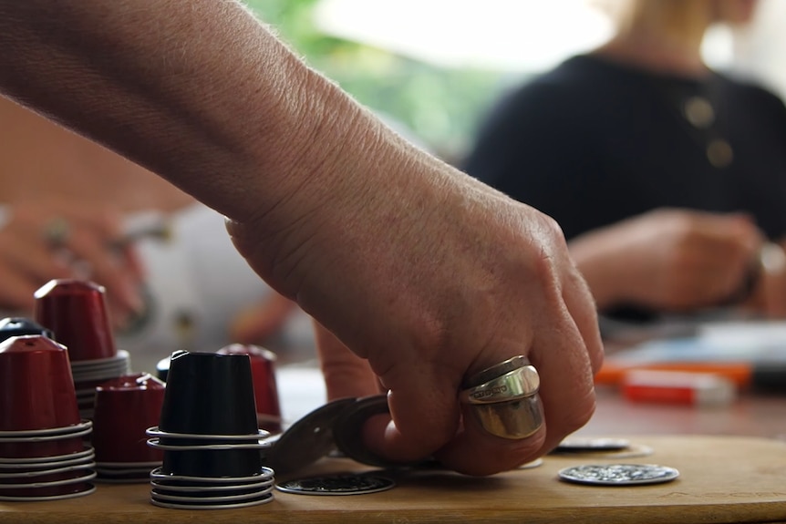 Hand reaches for coffee pod next to pile of used pods