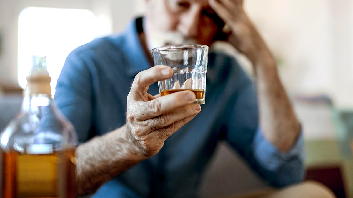 Drunk man drinking alcohol while holding a glass with alcohol