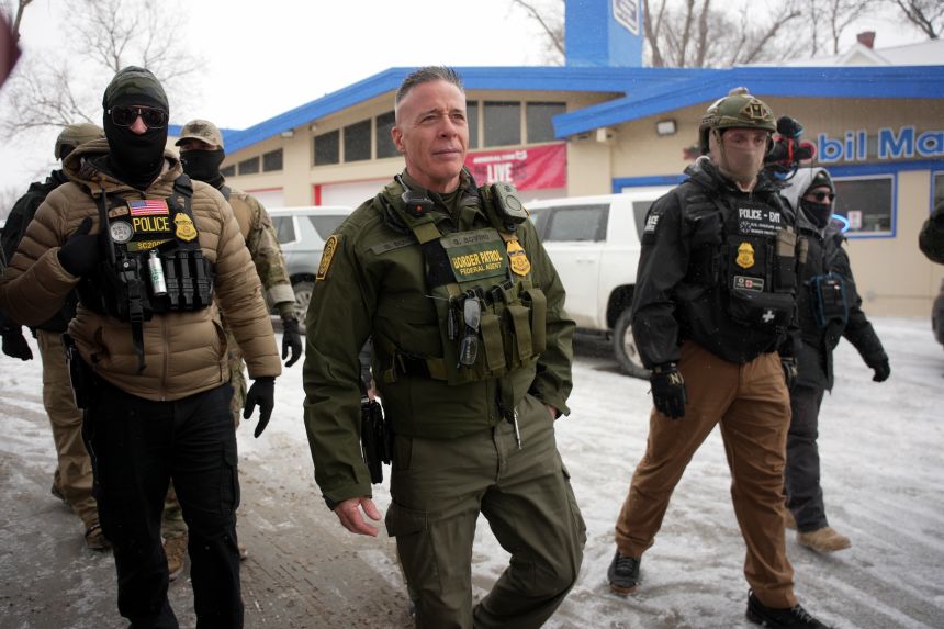 U.S. Border Patrol Cmdr. Gregory Bovino walks with Federal agents outside a convenience store on Wednesday, January 21, in Minneapolis.