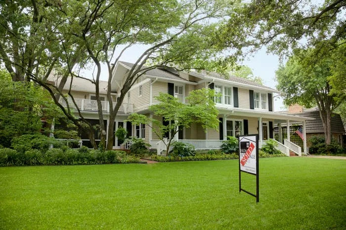 House with "Sold" sign on lush lawn, surrounded by trees. Ideal family home setting depicted