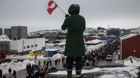 Reuters A woman waves a Greenlandic flag as people attend a protest against President Donald Trump's demand that the Arctic island be ceded to the US, in Nuuk, the capital of Greenland
