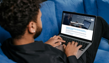 A man sitting on a couch using a laptop, exploring Northwood’s online master’s programs featured in U.S. News & World Report.